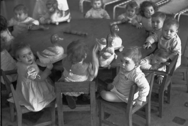 Sabadell - istituto di assistenza all'infanzia. Bambini piccoli seduti attorno a un tavolo