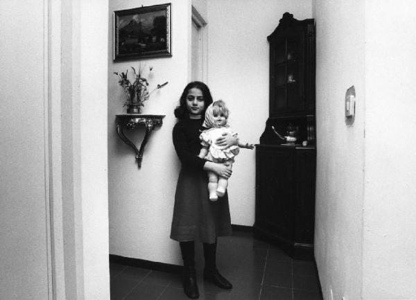 Terni - Quartiere Matteotti. Ragazza in posa nell'ingresso di casa propria con una bambola in mano