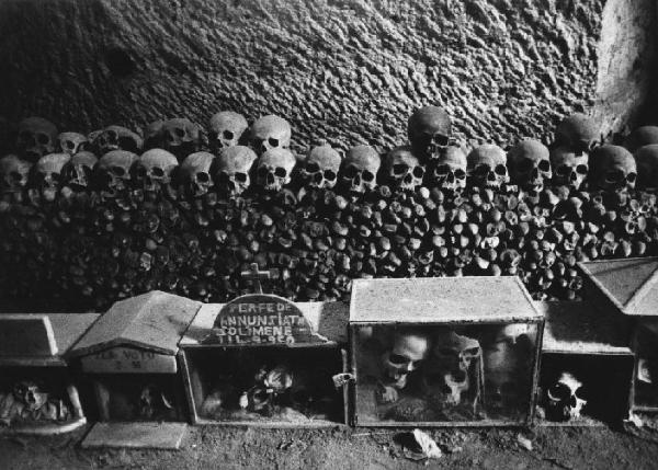 Culto ritualizzato dei morti. Napoli - Cimitero delle Fontanelle, interno - Teschi e tibie ammassati alla parete - Teche contenenti teschi e recanti inscrizioni di ex-voto