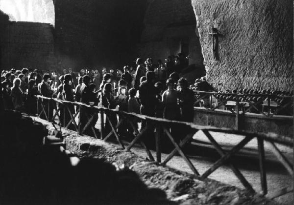 Culto ritualizzato dei morti. Napoli - Cimitero delle Fontanelle, interno - Devoti in fila con ceri in mano