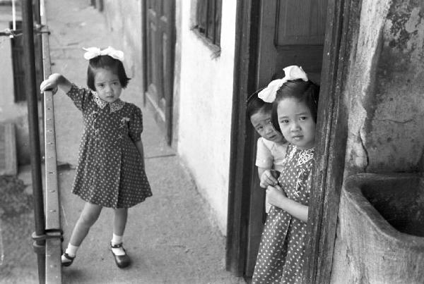 Italia Dopoguerra. Milano - Quartiere cinese - Casa di ringhiera - Ballatoio - Ritratto infantile: bambine cinesi