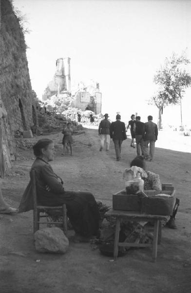 Italia Dopoguerra: Valmontone bombardata. Valmontone - Edifici distrutti - Strada - Ritratto femminile: donna con banchetto - Bombardamenti