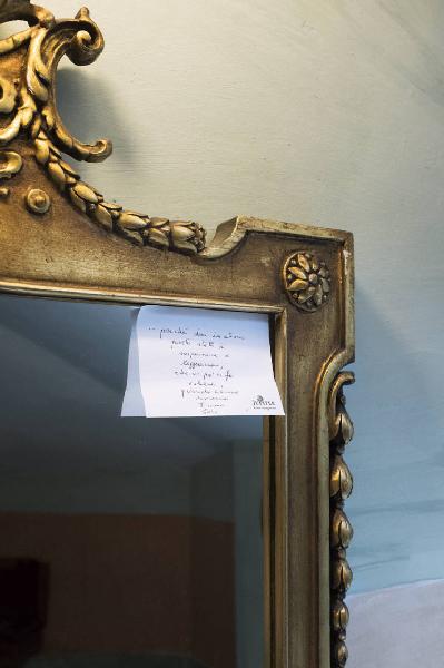 Check in': Un letto in mezzo ai fiori. Torino - Abitazione: interno - Post-it con dedica su angolo di uno specchio