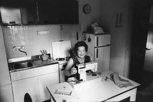 Una, nessuna, centomila. La Casa e i Riti. Milano - Cucina, interno - Ritratto femminile: ragazza con macchina da cucire