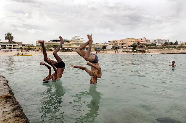 Migranti_Lampedusa. Lampedusa - Giornate dopo il naufragio del 3 ottobre 2013 - Mare - Spiaggia - Ritratto maschile: due ragazzi naufraghi, un somalo e un siriano, durante un tuffo