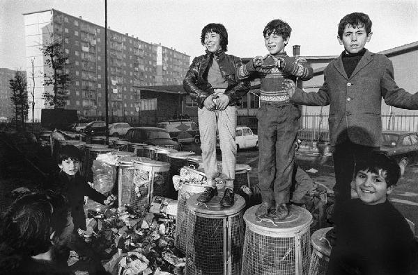 Altrove (1967-1980). Torino, via Artom - Ritratto di gruppo: bambini sui bidoni dell'immondizia - Esibizione di virilità - Palazzi sullo sfondo - Immigrazione dal sud Italia