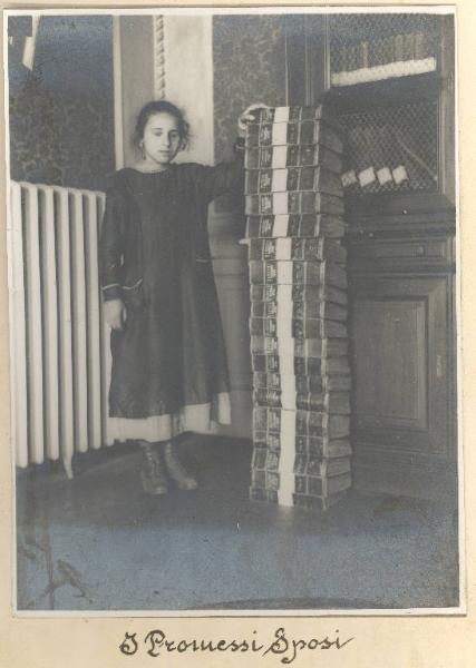 Istituto dei Ciechi di Milano - Scuola - Bambina cieca in piedi di fianco a una pila di volumi dei "Promessi sposi" trascritti in rilievo