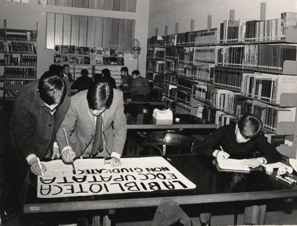 Milano - Quartiere Baggio - Biblioteca occupata - Interno - Giovani scrivono un cartello