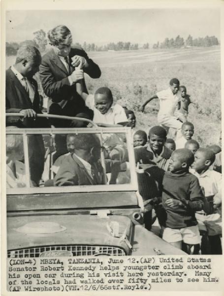 Mbeya - Visita in Tanzania - Robert Kennedy fa salire un giovane sulla jeep - Bambini corrono a fianco