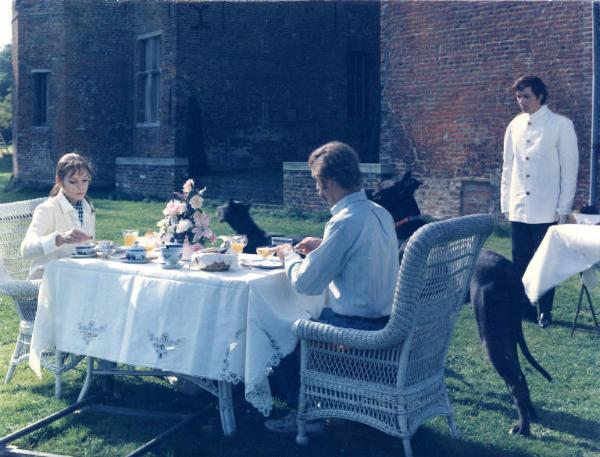 Scena del film "I tulipani di Haarlem" - Regia Franco Brusati - 1970 - Gli attori Carole Andrè e Gianni Garko seduti a un tavolo. Frank Grimes in piedi vestito da maggiordomo