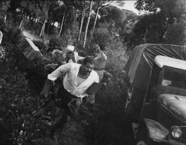 Scena del film "Senza pietà" - Regia Alberto Lattuada - 1948 - Gli attori Folco Lulli e John Kitzmiller e altri attori non identificati vicino a un camion nella pineta