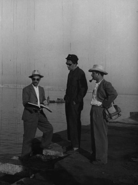 Set del film "Senza pietà" - Regia Alberto Lattuada - 1948 - Il regista Alberto Lattuada con il cappello e un copione e due persone non identificate