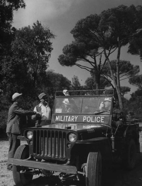 Set del film "Senza pietà" - Regia Alberto Lattuada - 1948 - Il regista Alberto Lattuada con attori non identificati in divisa su una camionetta militare