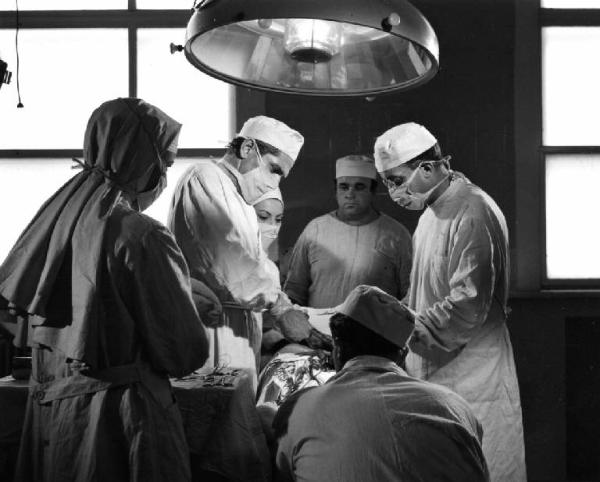 Scena del film "Anna" - Regia Alberto Lattuada - 1951 - Gli attori, Silvana Mangano, in veste di suora infermiera, Jacques Dumesnil, in camice bianco, in sala operatoria con l'infermiere Mimmo Poli e altri attori non identificati