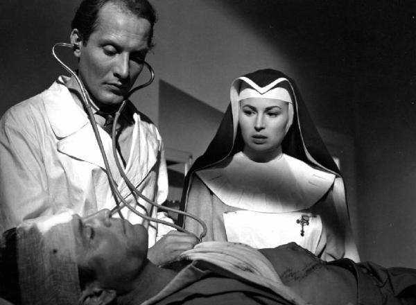 Scena del film "Anna" - Regia Alberto Lattuada - 1951 - L'attore Raf Vallone a letto malato assistito dagli attori Piero Lulli in camice bianco e Silvana Mangano in abito da suora infermiera