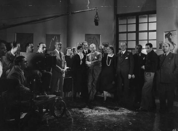 Set del film "La danza delle lancette" - Regia Mario Baffico - 1936 - Il regista Mario Baffico accanto alla macchina da presa sul set con gli attori del film e gli operatori della troupe.