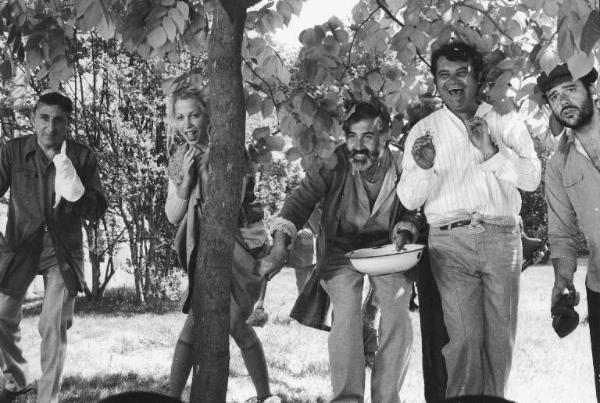 Set del film "Oh! Serafina" - Regia Alberto Lattuada - 1976 - L'attore Umberto Smaila e quattro attori non identificati sotto le foglie di un albero
