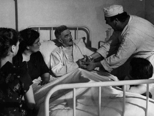 Scena del film "Anna" - Regia Alberto Lattuada - 1951 - L'attore Mimmo Poli, in abito da infermiere, assiste un paziente a letto in ospedale