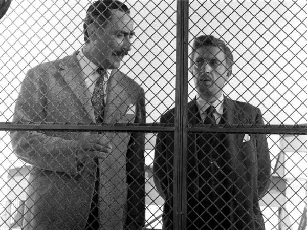 Scena del film "Anni facili" - Regia Luigi Zampa - 1953 - Gli attori Gino Buzzanca e Nino Taranto dietro una rete metallica