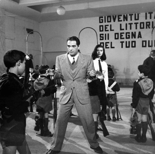 Scena del film "Anni ruggenti" - Regia Luigi Zampa - 1962 - L'attore Nino Manfredi ciscondato da bambini armati di fucile in divisa fascista