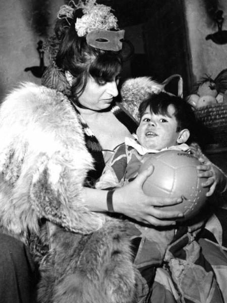 Scena del film "La carrozza d'oro" - Regia Jean Renoir - 1952 - L'attrice Anna Magnani con il bambino Dante in costume da arlecchino in braccio e una palla tra le mani