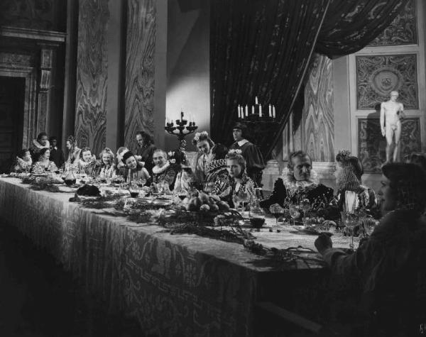Scena del film "Il cavaliere senza nome" - Regia Ferruccio Cerio - 1941 - Gli attori Mario Ferrari e Vera Carmi a tavola con attori non identificati