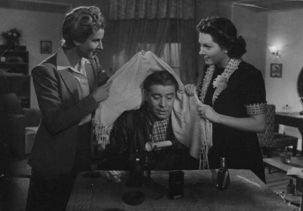 Scena del film "C'è sempre un ma!" - Regia Luigi Zampa - 1942 - Gli attori Rubi Dalma, un attore non identificato e Carla Del Poggio con una stola in mano