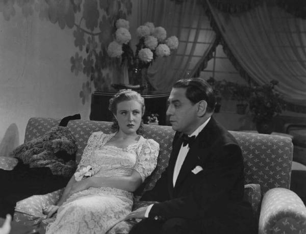 Scena del film "Chi è più felice di me?" - Regia Guido Brignone - 1938 - Gli attori Caterina Boratto e Tito Schipa seduti su un divano.