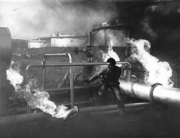 Scena del film "Il Cobra" - Regia Mario Sequi - 1967 - Un attore non identificato tra tubi in fiamme