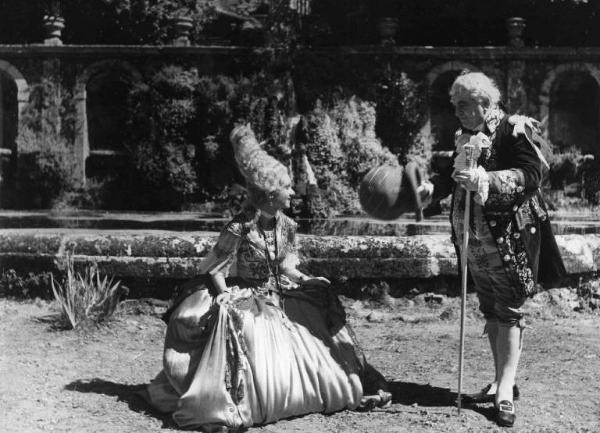 Scena del film "La conquista dell'aria" - Regia Romolo Marcellini - 1939 - Due attori non identificati, in fogge settecentesche, si salutano in giardino