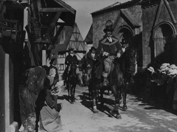 Scena del film "Il Conte di Brechard" - Regia Mario Bonnard - 1938 - L'attore Amedeo Nazzari e altri attori non identificati a cavallo passano tra la folla che s'inchina