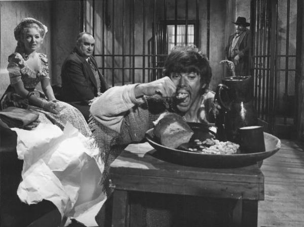 Set del film "Corri uomo corri" - Regia Sergio Sollima- 1968 - L'attrice Linda Veras e altri due attori non identificati osservano Tomas Milian mangiare all'interno di una cella carceraria.