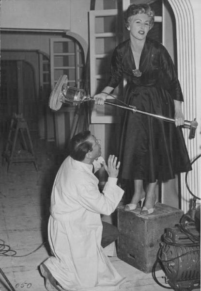 Set del film "Cose da pazzi" - Regia Georg Wilhelm Pabst - 1954- L'attrice Carla Del Poggio in piedi su una scatola tiene in mano un'asta con cui sembra minacciare l'attore Enrico Luzi.