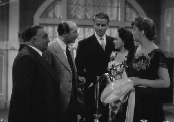 Set del film "Cose dell'altro mondo" - Regia Nunzio Malasomma - 1939- L'attore Amedeo Nazzari, l'attore Antonio Gandusio, l'attore Nino Pavese, l'attrice Cesarina Gheraldi e l'attrice Olga Solbelli parlano in un interno.