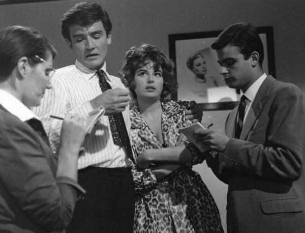 Set del film "Crimen" - Regia Mario Camerini- 1960 - L'attore Vittorio Gassman con l'attrice Silvana Mangano parlano e davanti a loro due attori non identificati scrivono su un taccuino
.