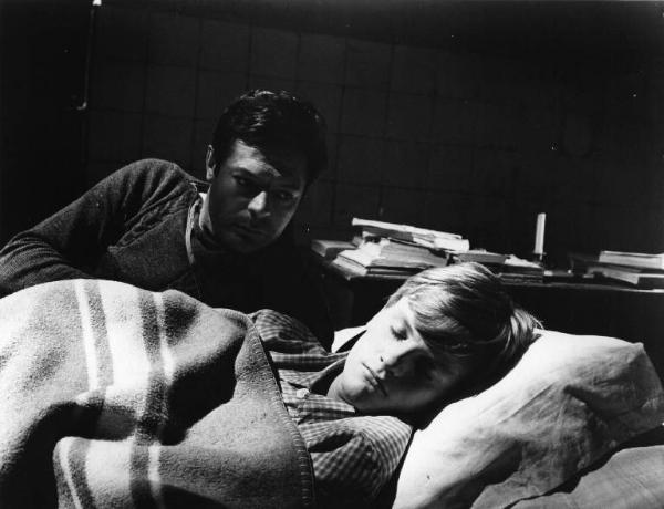 Set del film "Cronaca familiare" - Regia Valerio Zurlini 1962 - Su un letto in un interno l'attore Marcello Mastroianni è sdraiato accanto all'attore Jacques Perrin che dorme.