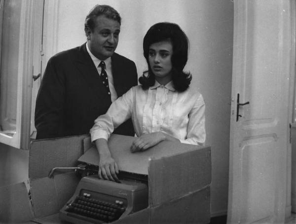 Fotografia del film "La cuccagna" - Regia Luciano Salce 1962 - L'attrice Donatella Turri e l'attore Umberto D'Orsi dietro una scatola contenente una macchina da scrivere.
.