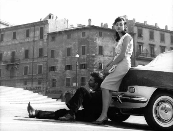 Fotografia del film "La cuccagna" - Regia Luciano Salce 1962 - L'attore Luigi Tenco seduto per terra accanto a Donatella Turri appogiati ad un'auto.
.