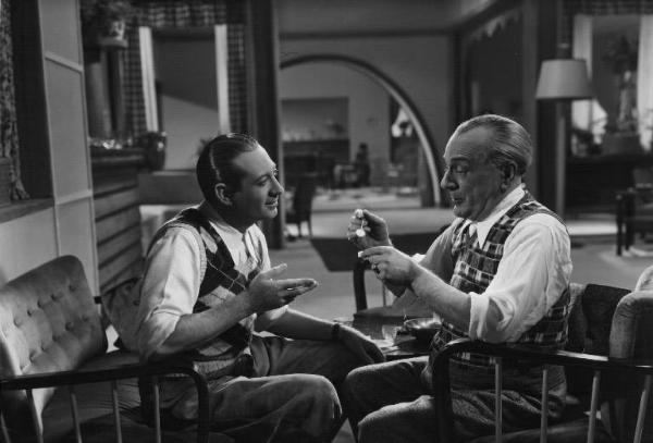 Fotografia del film "La dama bianca" - Regia Mario Mattoli 1938 - L'attore Nino Besozzi e l'attore Vincenzo Scarpetta dialogano seduti.