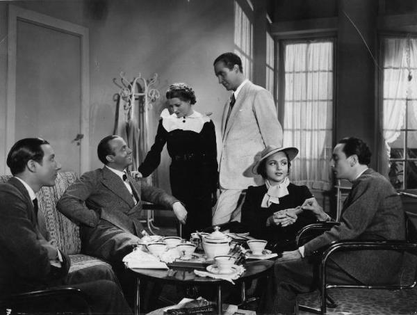Fotografia del film "La danza delle lancette" - Regia Mario Baffico 1936 - L'attore Marcello Spada e l'attrice Barbara Moris con altri attori non identificati in un salotto.
