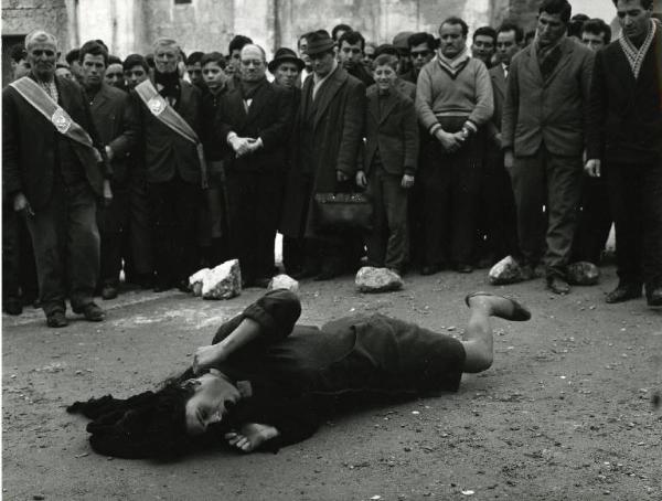 Scena del film "Il demonio" - Regia Brunello Rondi, 1963 - Daliah Lavi sdraiata a terra, urla, scalcia e si dimena. Una folla di curiosi, attorno a lei la guarda divertita.