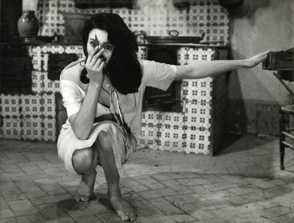 Scena del film "Il demonio" - Regia Brunello Rondi, 1963 - Daliah Lavi accovacciata a terra tiene un paio di forbici sul naso, le lame sono semiaperte in coincidenza delle estremità delle sopracciglia.