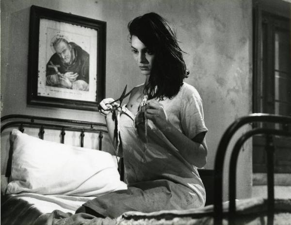 Scena del film "Il demonio" - Regia Brunello Rondi, 1963 - Daliah Lavi, inginocchiata sul letto, si lacera il vestito con delle forbici.