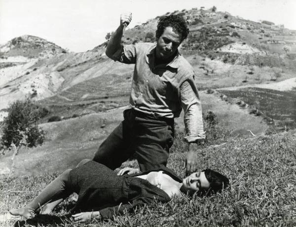 Scena del film "Il demonio" - Regia Brunello Rondi, 1963 - Su un prato in collina, Frank Wolff inchinato alza il coltello per colpire Daliah Lavi. L'attrice giace svenuta a terra supina con il vestito aperto sul petto.