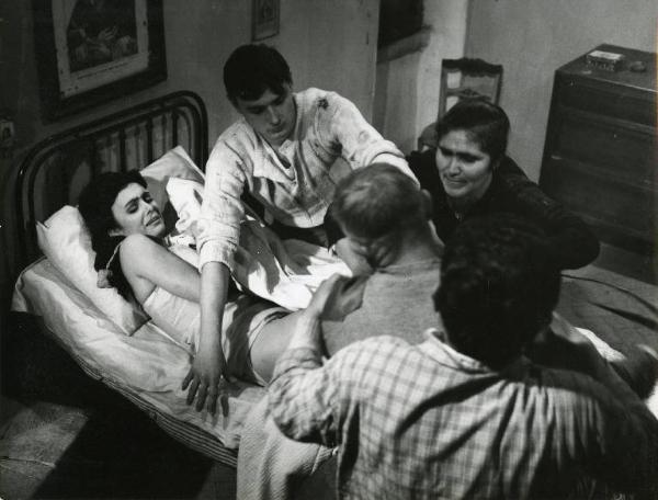 Scena del film "Il demonio" - Regia Brunello Rondi, 1963 - Daliah Lavi distesa a letto, in mutande e canottiera, viene aggredita da un uomo trattenuto per le spalle da un altro. Un terzo uomo le fa scudo con le braccia, al suo fianco una donna.