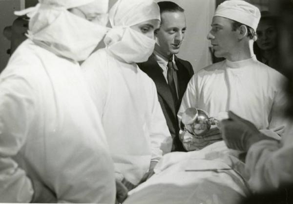 Sul set del film "Diagnosi" - Regia Ferruccio Cerio, 1942 - Tre attori in costume di scena e un uomo in giacca e cravatta in una pausa di lavorazione del film.