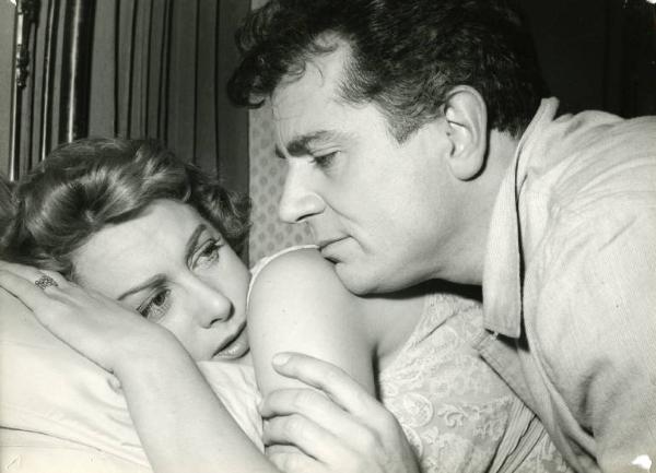 Scena del film "Difendo il mio amore" - Regia Giulio Macchi, 1956 - Martine Carol, stesa a letto, appoggia la testa sul cuscino. Gabriele Ferzetti, sdraiato su di lei, appoggia il mento sulla sua spalla. I due si guardano.