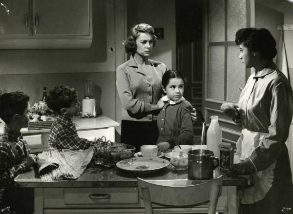 Scena del film "Difendo il mio amore" - Regia Giulio Macchi, 1956 - Martine Carol tiene Maria Del Gesso per le spalle, entrambe, guardano verso la governante, sulla destra, che ricambia lo sguardo. A sinistra due bambini vestiti uguali.