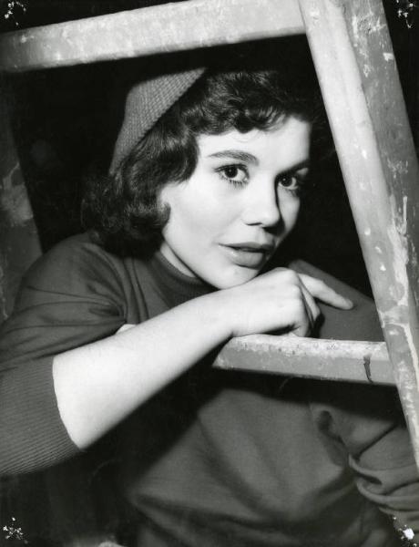 Scena del film "Difendo il mio amore" - Regia Giulio Macchi, 1956 - Mezza figura di Giorgia Moll, seduta e appoggiata con il braccio destro su una scala a pioli.