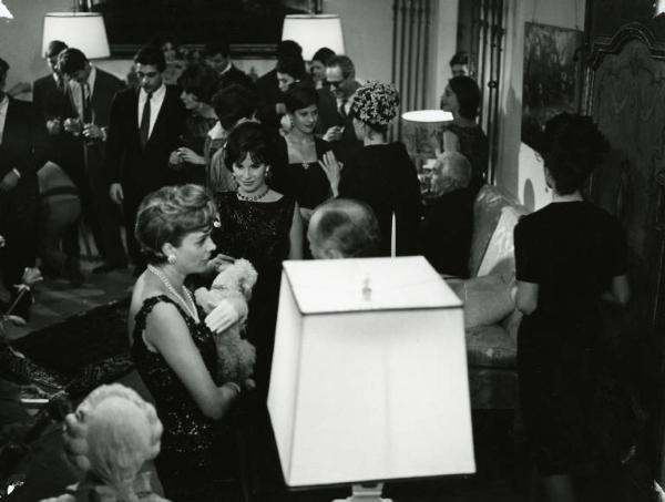 Scena del film "Il disordine" - Regia Franco Brusati, 1962 - Antonella Lualdi, in abito da sera è al centro di un gruppo di persone durante una festa in casa.